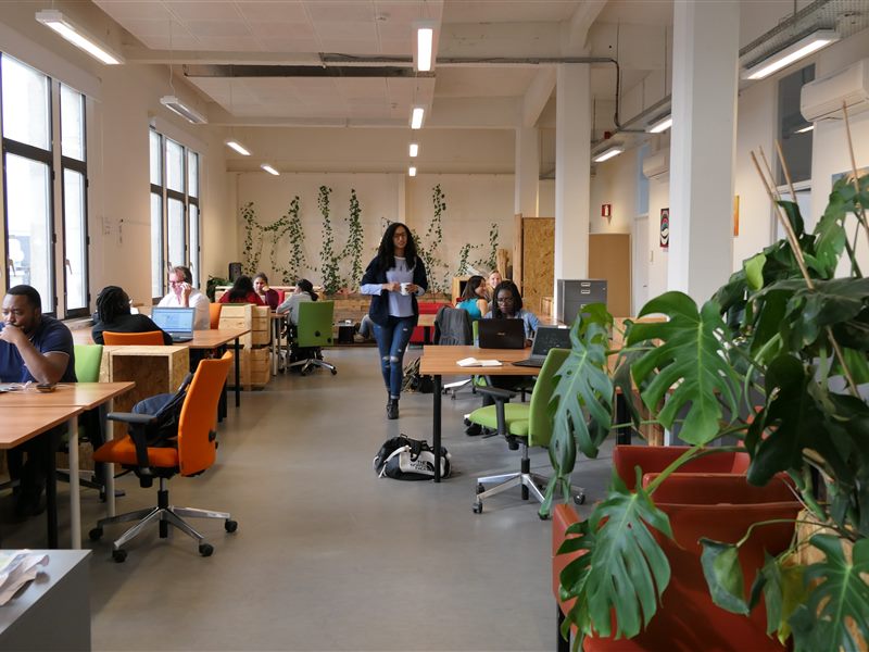 Open-plan hot desk area with rows of shared desks and natural light