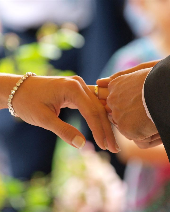 Groom placing an engagement ring on the bride's finger