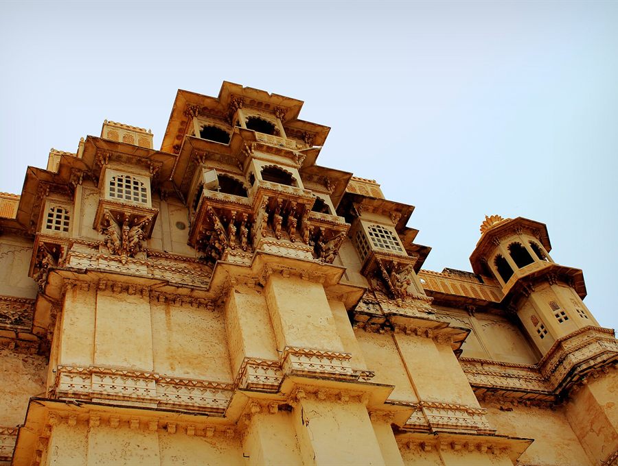 Ornate sandstone palace facade with carved balconies against a blue sky