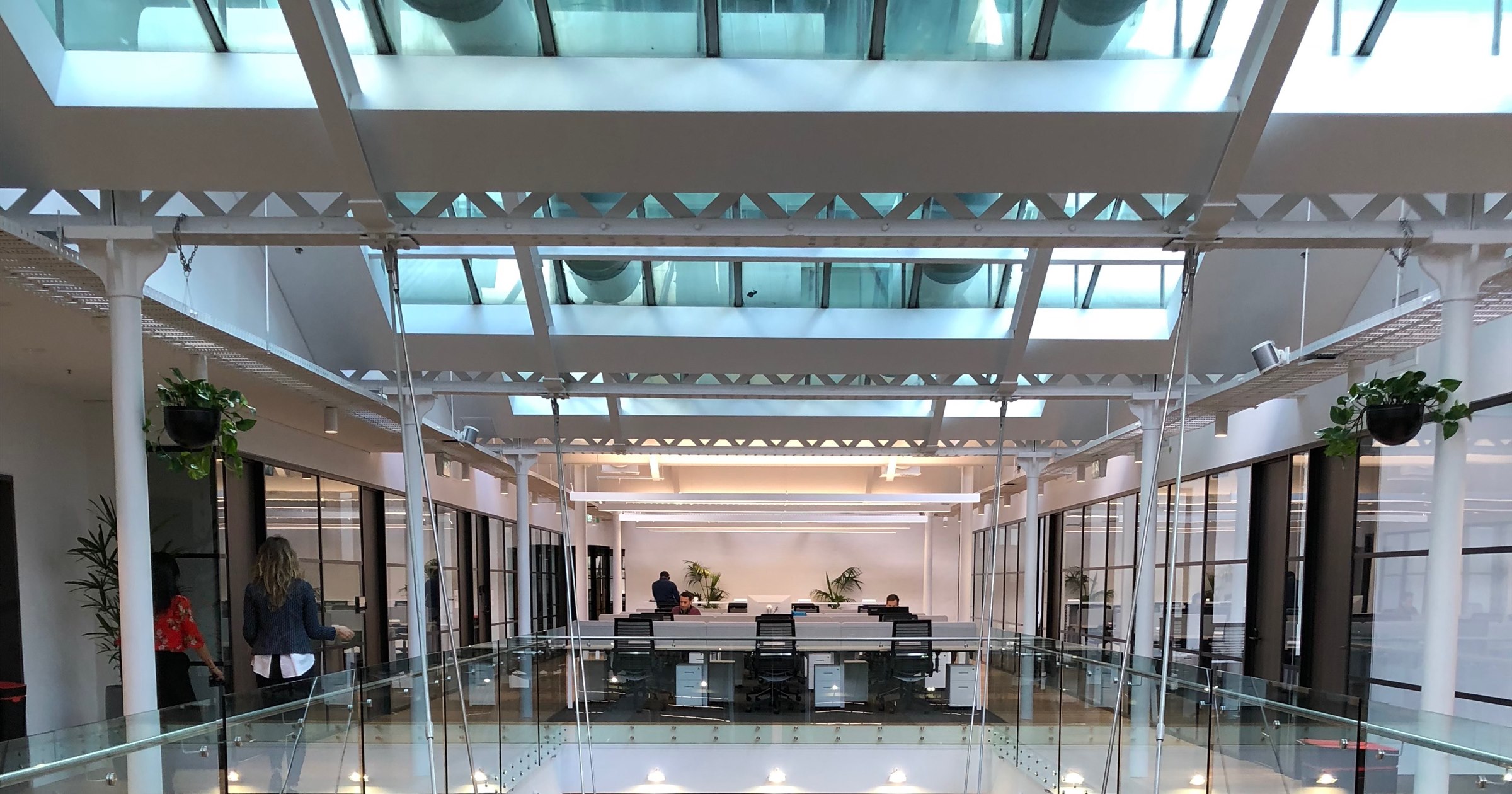 Bright multi-level coworking space with a glass skylight atrium, open desks and glass railings