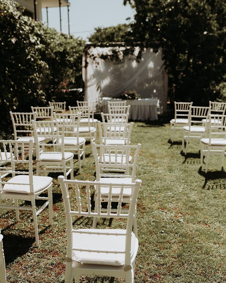 White chairs arranged on a lawn for an intimate garden wedding ceremony